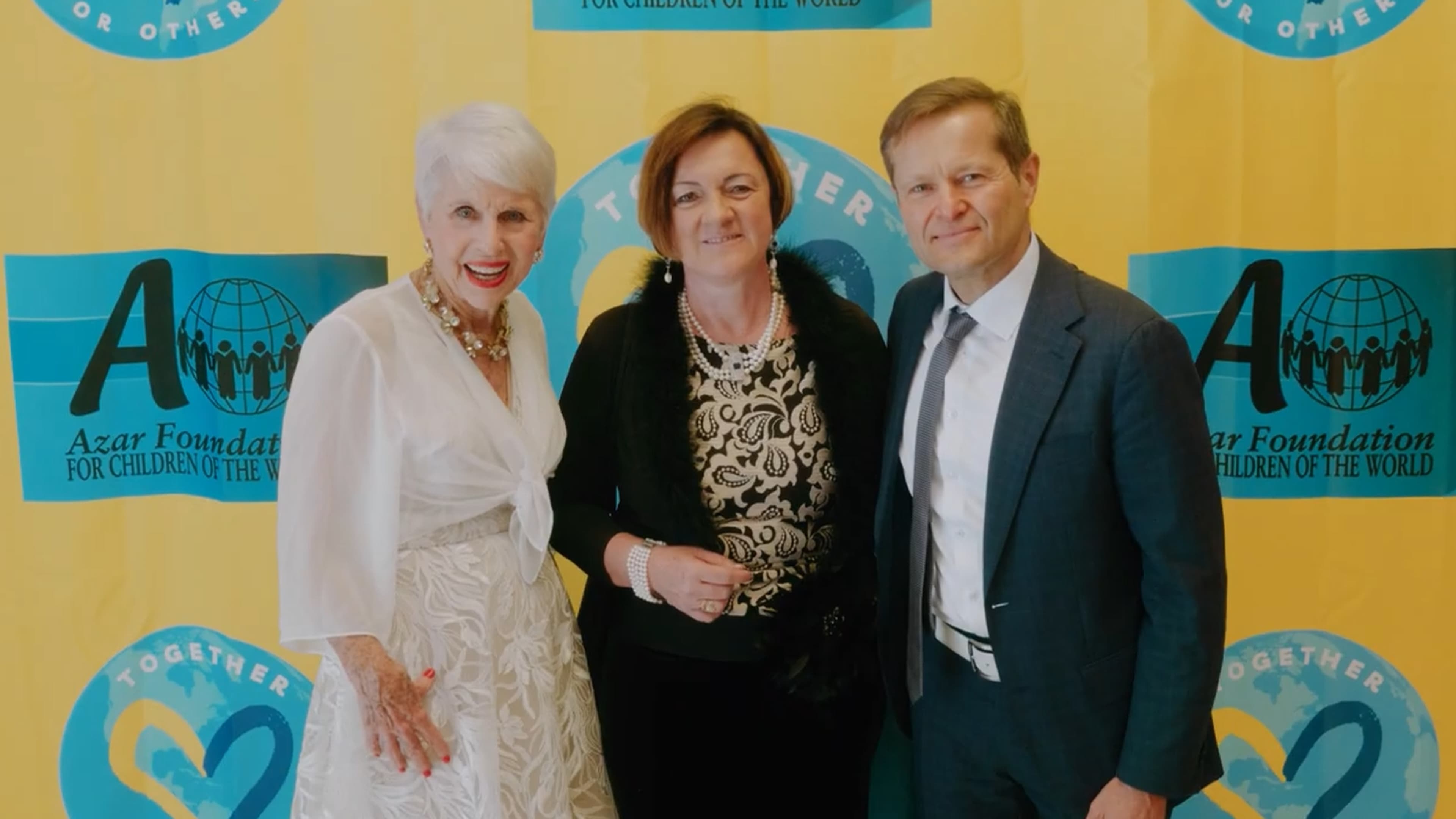 Guests posing in front of the Together for Others banner