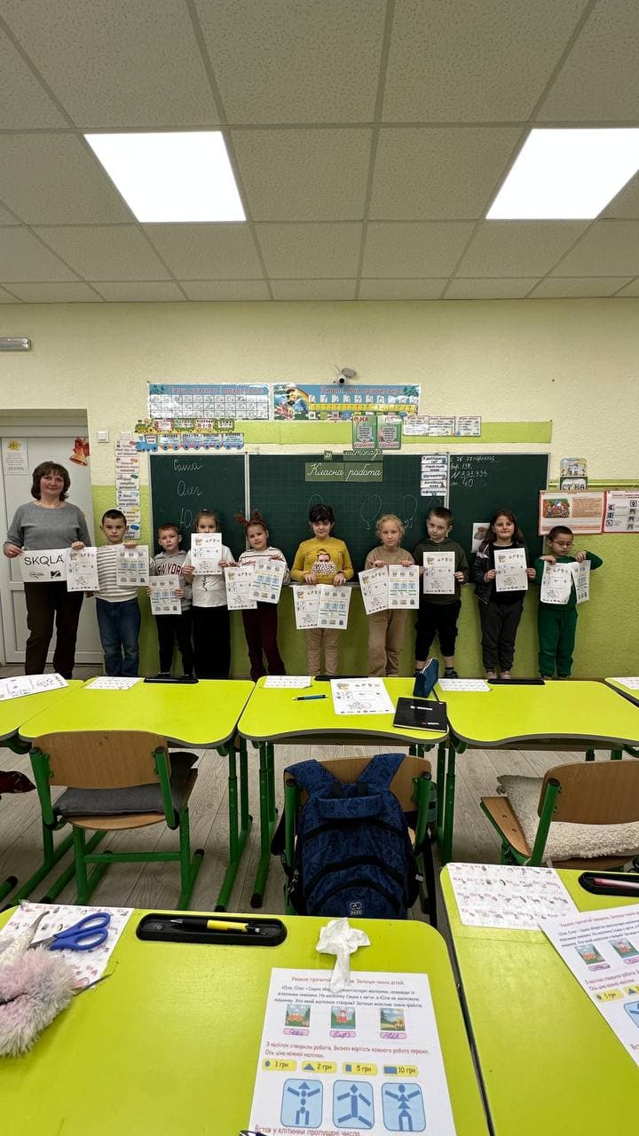 Students in a SKOLKA classroom holding up their worksheets