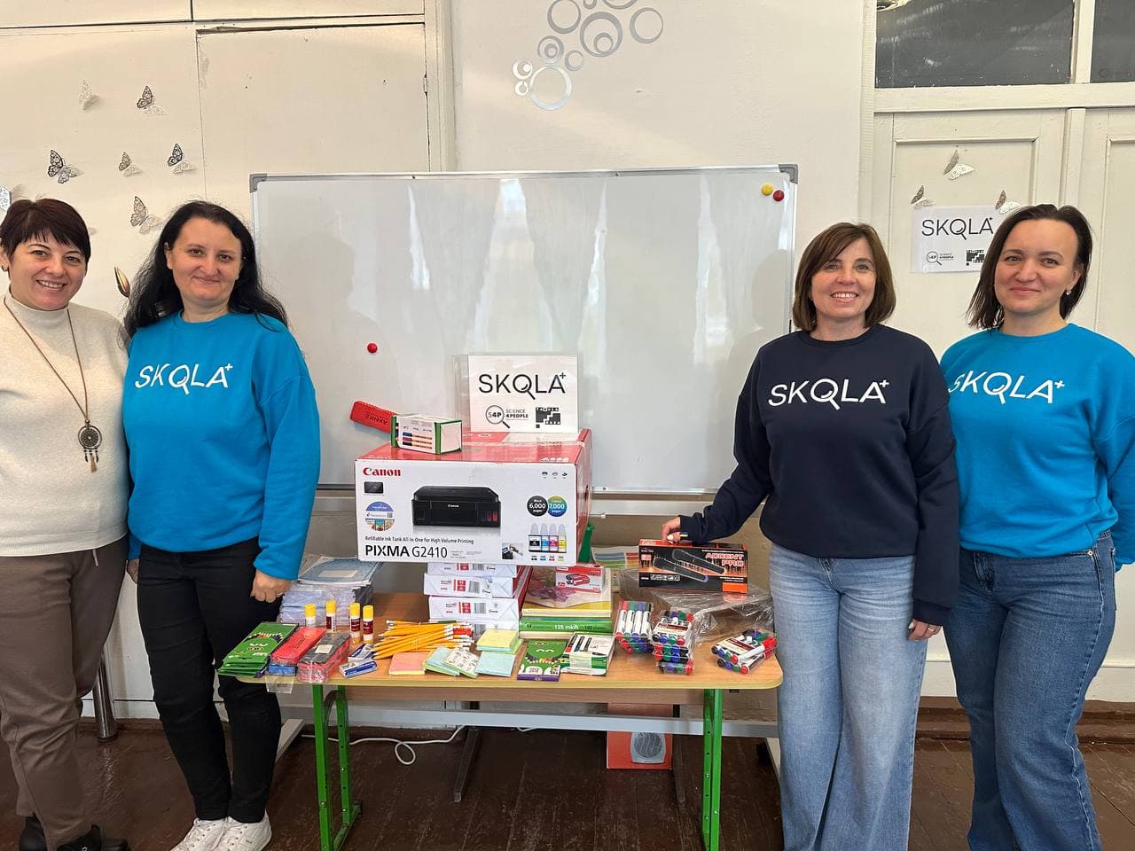 Four SKOLKA volunteers presenting a new Canon printer and school supplies in a Ukrainian classroom