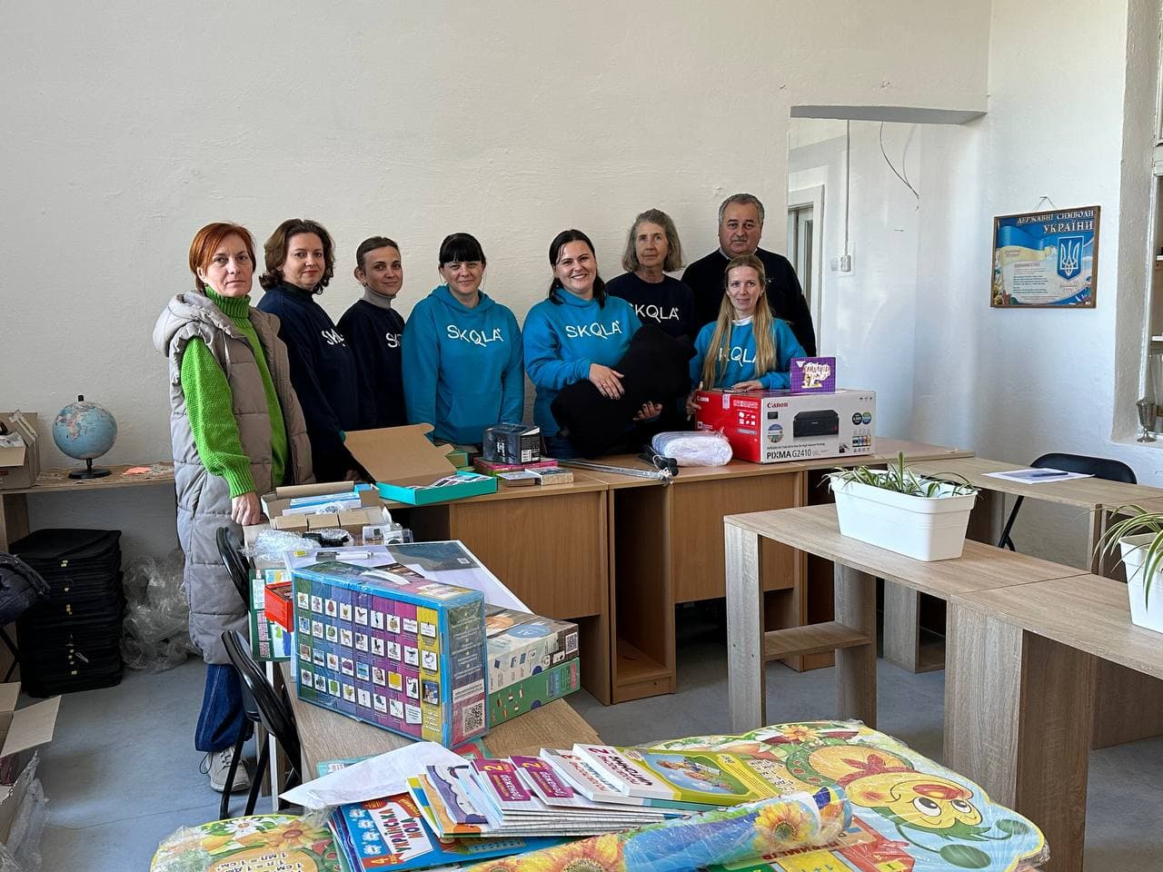 SKOLKA team members delivering educational supplies including a printer and teaching materials to a Ukrainian school
