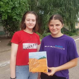 Two students from Marhanets holding a handmade painting of a wheat field