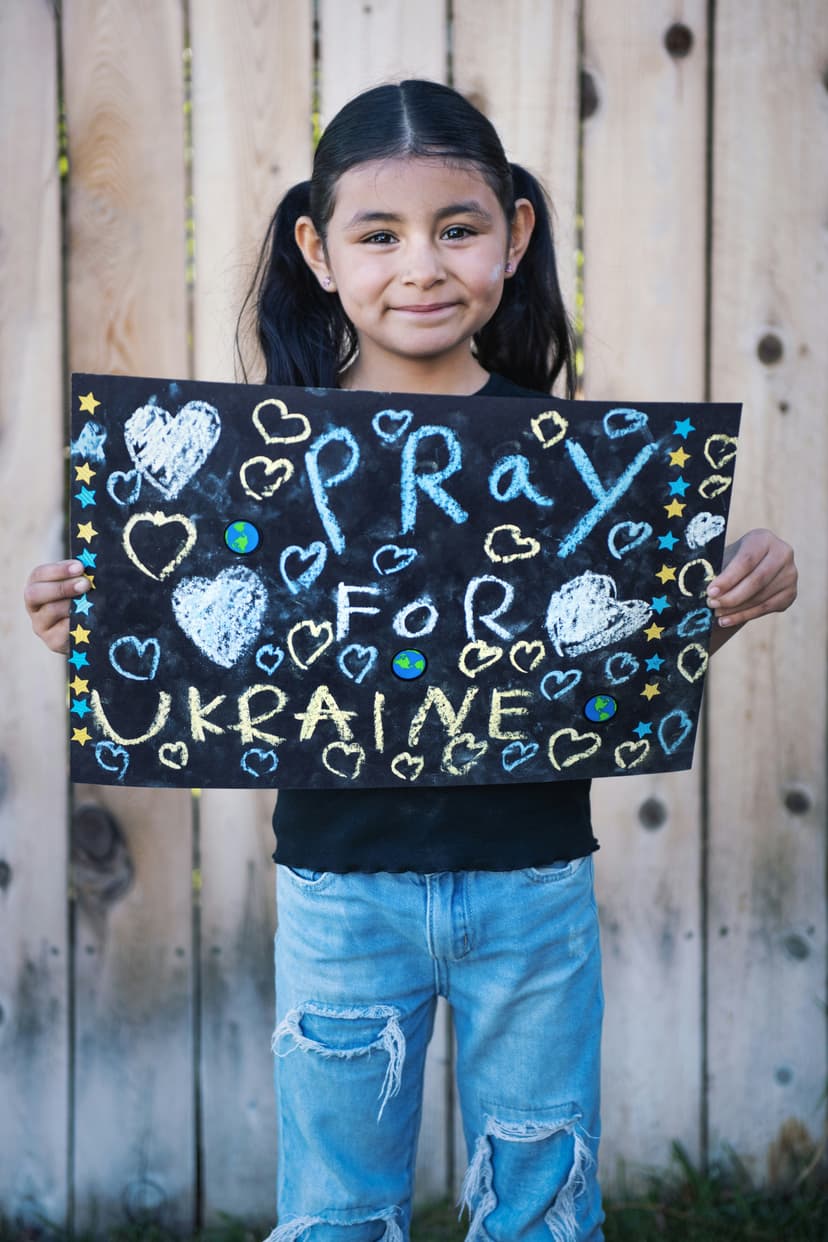 Young girl holding a handmade sign reading Pray for Ukraine
